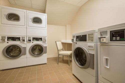 a laundry room with two machines and a chair at Homewood Suites Midtown Manhattan Times Square South in New York