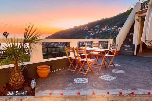 a table and chairs on the balcony of a house at BnB BananaTree House in Arco da Calheta