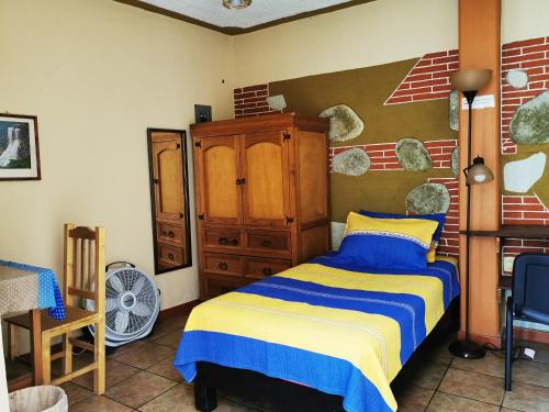 a bedroom with a bed and a wooden cabinet at Casa Donaji in Oaxaca City