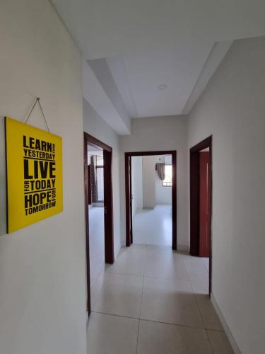 an empty hallway with a yellow sign on a wall at Three Bed Attached Bath Netflix Wifi Smart TV Parking WFH Desk Near Airport in Islamabad