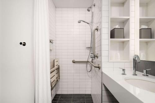 a white bathroom with a shower and a sink at Motto by Hilton Philadelphia Rittenhouse Square in Philadelphia
