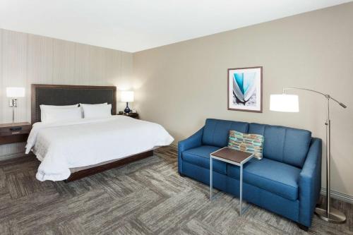 Habitación de hotel con cama y sofá azul en Hampton Inn Kennebunk Kennebunkport Me en Kennebunk