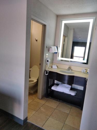 a bathroom with a sink and a mirror and a toilet at Days Inn & Suites by Wyndham Albuquerque North in Albuquerque