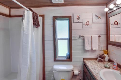 a bathroom with a toilet and a sink and a window at Mayfield Tiny Home with Porch, Walk to Beaches! in Benson