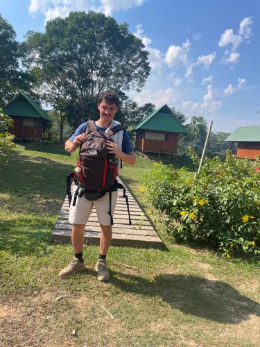 a man with a backpack standing in the grass at Sunrise of Tambopata in Puerto Maldonado