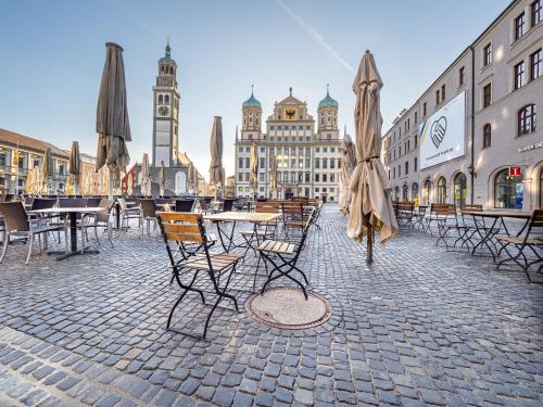 a group of tables and chairs with umbrellas on a street at TRULY - Direkt am Rathausplatz, Dachterrasse mit Blick auf Perlachturm, Garage, Fahrstuhl in Augsburg