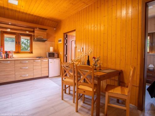 a kitchen with a wooden table and wooden chairs at Domek letniskowy in Władysławowo