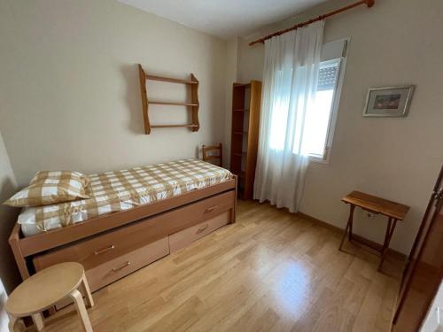 a bedroom with a bed and a table and a window at Apartamento Vallehermoso in El Puerto de Santa María