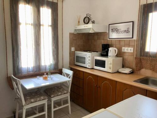 a kitchen with a counter with a microwave and a table at Kalliopi's House in Mandrakion