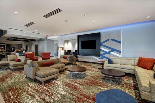 a large living room with couches and a flat screen tv at Hilton Garden Inn Lansing West in Lansing