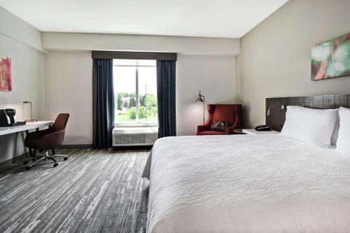 a hotel room with a bed and a desk and a window at Hilton Garden Inn Lansing West in Lansing