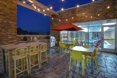 a restaurant with yellow chairs and tables and a red umbrella at Home2 Suites by Hilton Troy in Troy