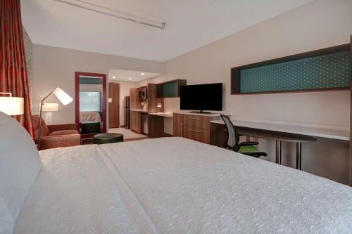 a hotel room with a bed and a flat screen tv at Home2 Suites by Hilton Troy in Troy