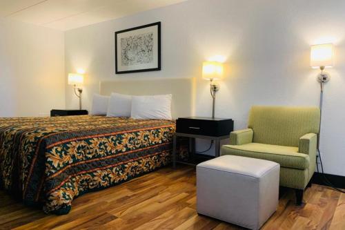 Habitación de hotel con cama y silla en Economy Inn by OYO Holland, en Holland