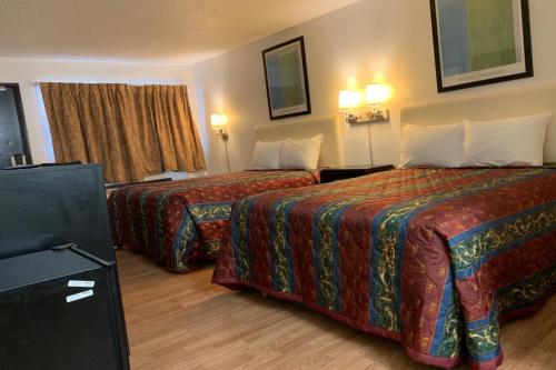 a hotel room with two beds and a television at Economy Inn of Holland in Holland