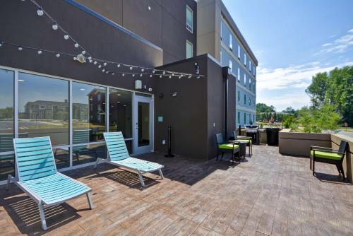 a patio outside of a building with blue chairs at Home2 Suites By Hilton Rock Hill in Rock Hill