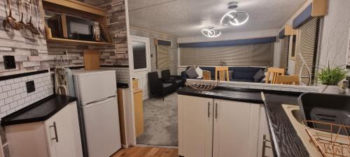 a kitchen with a refrigerator and a living room at ML66 8 BERTH CARAVAN GOLDEN PALM CHAPEL ST LEONARDS in Chapel Saint Leonards
