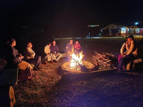 a group of people sitting around a fire at HOSTERÍA BRISAS DEL RÍO in Marinilla