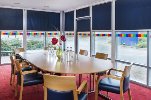 a dining room with a table and chairs and windows at Park Inn by Radisson Birmingham Walsall in Walsall