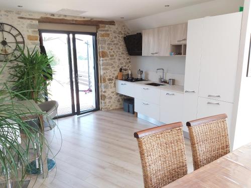 une cuisine avec des armoires blanches et une table avec des chaises dans l'établissement Maison entourée d animaux en pleine campagne, à Lasseube