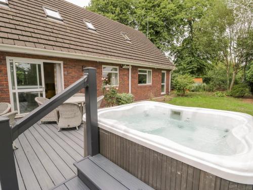 a hot tub on the deck of a house at Woodlands Retreat in Ruthin