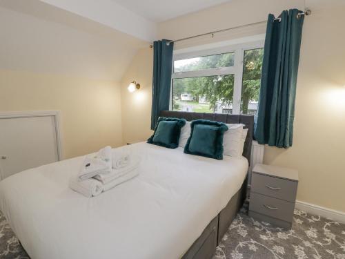 a bedroom with a large bed with blue curtains and a window at Woodlands Retreat in Ruthin