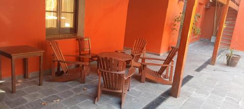una habitación con sillas y una mesa con una pared de color naranja en Hotel Beltran, en Colonia del Sacramento