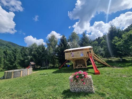a playground in a field with a play structure at Căsuța dintre brazi in Râşnov