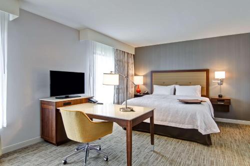 a hotel room with a bed and a desk and a television at Hampton Inn & Suites Detroit/Troy in Clawson