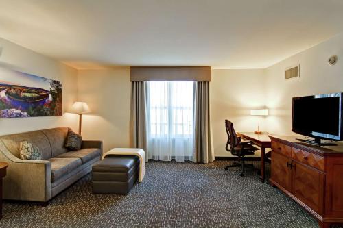 a hotel room with a couch and a desk and a television at Homewood Suites by Hilton Bentonville-Rogers in Rogers