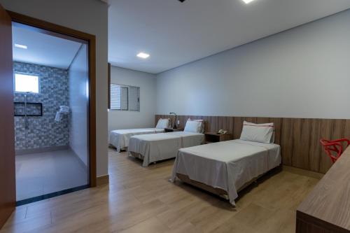 a hotel room with two beds and a window at Hotel Rio Vermelho in Goiânia