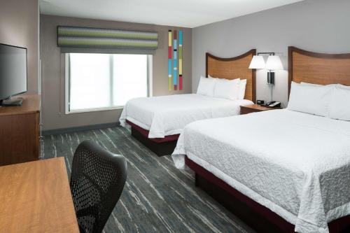 a hotel room with two beds and a flat screen tv at Hampton Inn & Suites Chicago North Shore in Skokie