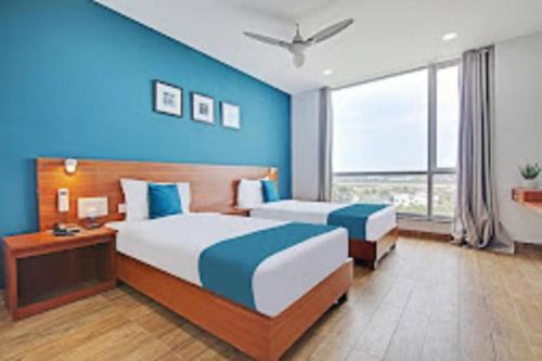 um quarto com 2 camas e uma parede azul em DSquare- OMR em Chennai