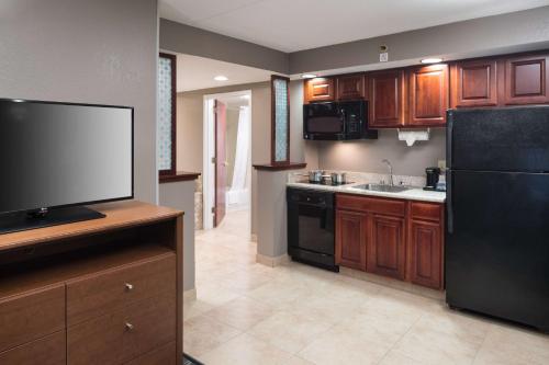 a kitchen with a black refrigerator and a tv at Hampton Inn & Suites Chicago North Shore in Skokie