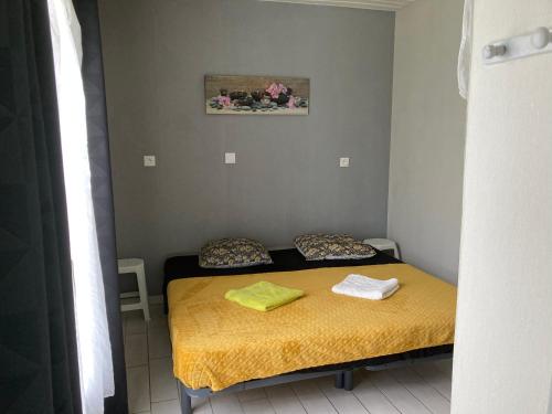 a small bedroom with a bed with yellow sheets and towels at F1 noir/anis, avec terrasse couverte et jardin (E) in Compreignac