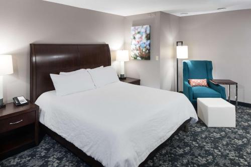 a hotel room with a bed and a blue chair at Hilton Garden Inn Cincinnati/Mason in Mason