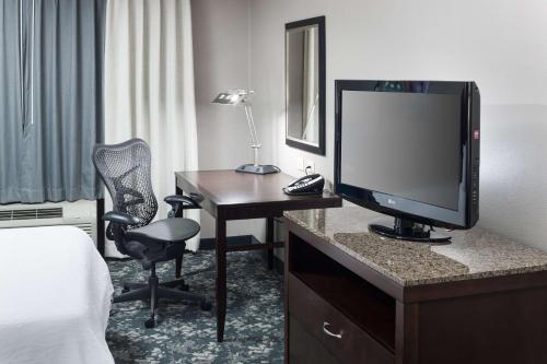 a hotel room with a desk with a television and a bed at Hilton Garden Inn Cincinnati/Mason in Mason