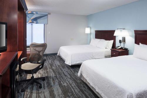 Habitación de hotel con 2 camas, escritorio y silla en Hampton Inn Kansas City Liberty en Liberty