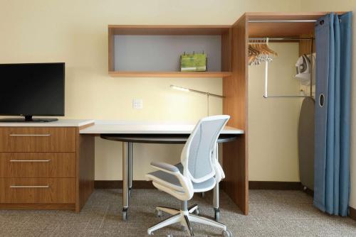 a desk with a television and two white chairs at Home2 Suites by Hilton Milwaukee Airport in Milwaukee