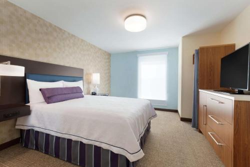 a hotel room with a bed and a flat screen tv at Home2 Suites by Hilton Milwaukee Airport in Milwaukee