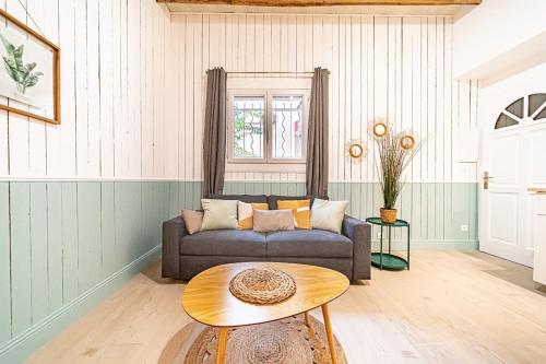 een woonkamer met een bank en een tafel bij La Maison Charpennes-appartement Eucalyptus 4 pers in Villeurbanne