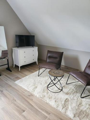 a living room with two chairs and a tv at Chez Pascale in Le Molay-Littry