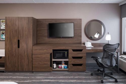 a room with a desk with a television and a chair at Hampton Inn Bentonville-Rogers in Rogers