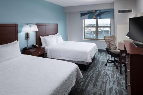 ein Hotelzimmer mit 2 Betten, einem Schreibtisch und einem TV in der Unterkunft Hampton Inn & Suites Oklahoma City-Bricktown in Oklahoma City