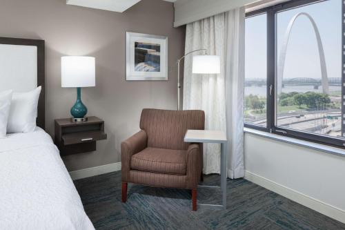 Hampton Inn St Louis- at the Arch في سانت لويس: غرفة نوم بسرير وكرسي ونافذة