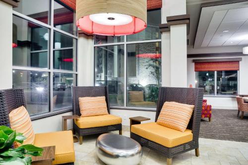 a lobby with two chairs and a table and windows at Hilton Garden Inn North Houston Spring in Spring