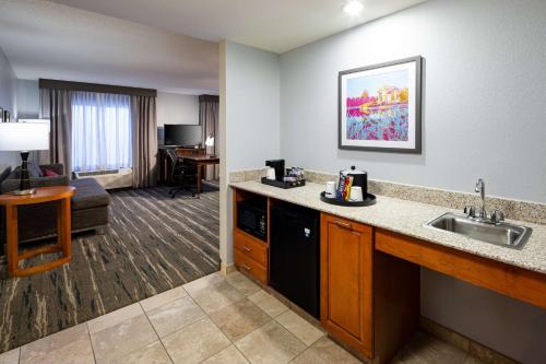 um quarto de hotel com um lavatório e uma sala de estar em Hampton Inn & Suites St. Louis at Forest Park em Saint Louis