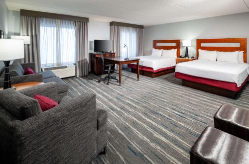 セントルイスにあるHampton Inn & Suites St. Louis at Forest Parkのベッド2台とソファが備わるホテルルームです。