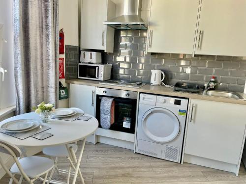 uma cozinha com uma mesa, um fogão e um micro-ondas em Cheerful 1 Bed Apartment Cardiff City Centre - Penarth Rd em Cardiff
