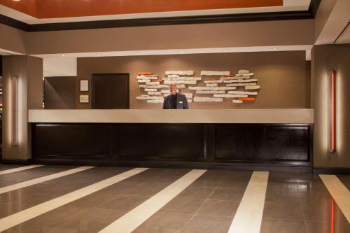 a man standing at a counter in a lobby at Embassy Suites by Hilton Austin Arboretum in Austin